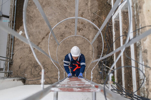 Инженер по обеспечению полной безопасности при подъеме по лестнице к сигналам связи и промышленному оборудованию на транспортном объекте с высоким риском