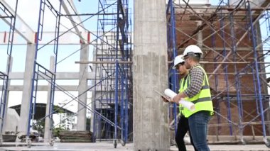 İki inşaat işçisi şantiyede duruyor ve çalışma planlarını tartışıyorlar.
