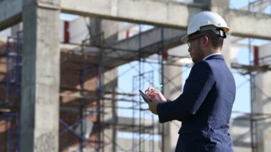 İnşaat alanında tablet kullanan güvenlik kasklı mühendis.