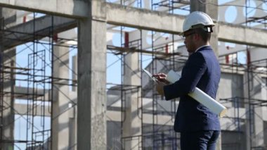 İnşaat alanında tablet kullanan güvenlik kasklı mühendis.