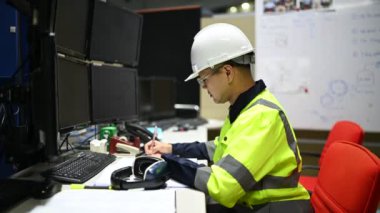 Kasklı genç mühendis endüstriyel odada çalışıyor..