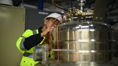 Ameliyathanedeki Asyalı mühendis özen ve sabırla çalıştı. Hidrojen tankındaki valf düzenleyicisini kontrol etti..