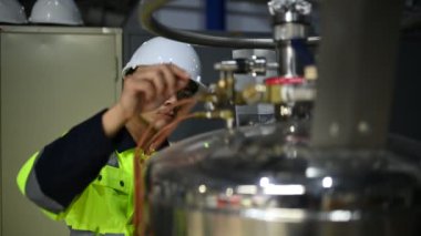 Ameliyathanedeki Asyalı mühendis özen ve sabırla çalıştı. Hidrojen tankındaki valf düzenleyicisini kontrol etti..