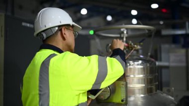 Ameliyathanedeki Asyalı mühendis özen ve sabırla çalıştı. Hidrojen tankındaki valf düzenleyicisini kontrol etti..