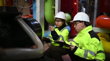 Fabrikadaki petrol ve gaz boru hatlarını kontrol eden iki mühendis.