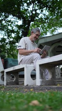 Parkta dijital tablet kullanan kıdemli adam