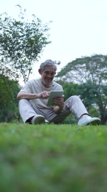 Parktaki çimlerde dijital tablet kullanan adam