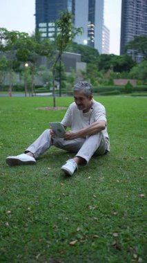 Parktaki çimlerde dijital tablet kullanan adam
