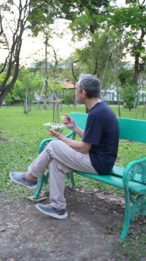 Son sınıf öğrencisi parkta bankta otururken sağlıklı salata yiyor.