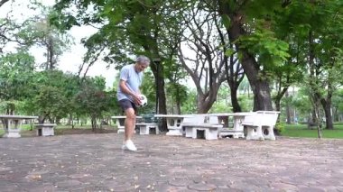 Yetişkin Asyalı son sınıf öğrencisi parkta futbol topuyla oynuyor..