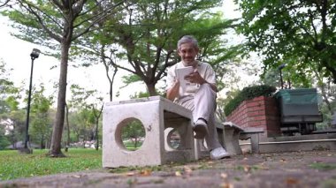 Parkta dijital tablet kullanan kıdemli adam