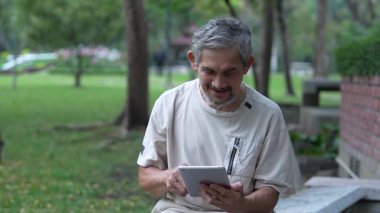 Parkta dijital tablet kullanan kıdemli adam