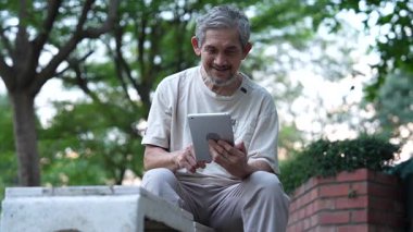 Parkta dijital tablet kullanan kıdemli adam