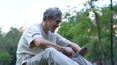 Parktaki çimlerde dijital tablet kullanan adam