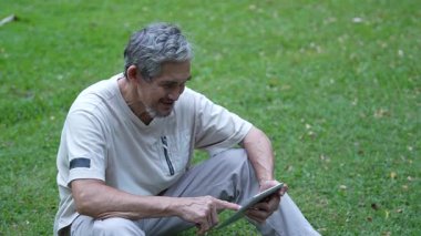 Parktaki çimlerde dijital tablet kullanan adam