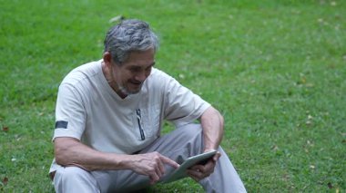 Parktaki çimlerde dijital tablet kullanan adam