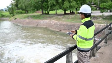 Çevre mühendisi su kalitesini denetliyor ve açık havada dijital tablet kullanıyor