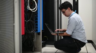 erkek mühendis sunucu odasında dizüstü bilgisayarla çalışıyor