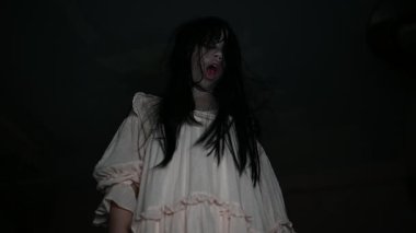 Yüzünde hayalet resmi olan korkunç kadın karanlıkta poz veriyor.