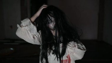 Yüzünde hayalet resmi olan korkunç kadın karanlıkta poz veriyor.