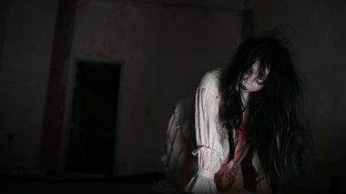 Yüzünde hayalet resmi olan korkunç kadın karanlıkta poz veriyor.