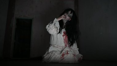 Yüzünde hayalet resmi olan korkunç kadın karanlıkta poz veriyor.