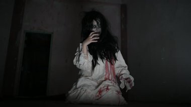 Yüzünde hayalet resmi olan korkunç kadın karanlıkta poz veriyor.