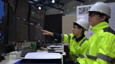 Büyük Endüstri Fabrikası Erkek Bilgisayar Mühendisleri Kişisel Bilgisayarlar üzerinde çalışıyor kontrol makinesi için kodlama programı, Taylandlılar dört monitör ve ciddi bir programcıyla çalışıyorlar.