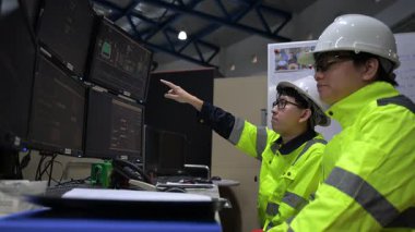 Büyük Endüstri Fabrikası Erkek Bilgisayar Mühendisleri Kişisel Bilgisayarlar üzerinde çalışıyor kontrol makinesi için kodlama programı, Taylandlılar dört monitör ve ciddi bir programcıyla çalışıyorlar.