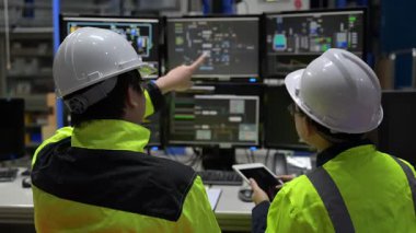 Büyük Endüstri Fabrikası Erkek Bilgisayar Mühendisleri Kişisel Bilgisayarlar üzerinde çalışıyor kontrol makinesi için kodlama programı, Taylandlılar dört monitör ve ciddi bir programcıyla çalışıyorlar.