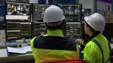 Büyük Endüstri Fabrikası Erkek Bilgisayar Mühendisleri Kişisel Bilgisayarlar üzerinde çalışıyor kontrol makinesi için kodlama programı, Taylandlılar dört monitör ve ciddi bir programcıyla çalışıyorlar.