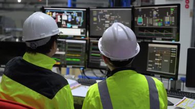 Büyük Endüstri Fabrikası Erkek Bilgisayar Mühendisleri Kişisel Bilgisayarlar üzerinde çalışıyor kontrol makinesi için kodlama programı, Taylandlılar dört monitör ve ciddi bir programcıyla çalışıyorlar.