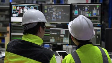 Büyük Endüstri Fabrikası Erkek Bilgisayar Mühendisleri Kişisel Bilgisayarlar üzerinde çalışıyor kontrol makinesi için kodlama programı, Taylandlılar dört monitör ve ciddi bir programcıyla çalışıyorlar.