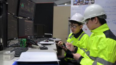 Büyük Endüstri Fabrikası Erkek Bilgisayar Mühendisleri Kişisel Bilgisayarlar üzerinde çalışıyor kontrol makinesi için kodlama programı, Taylandlılar dört monitör ve ciddi bir programcıyla çalışıyorlar.