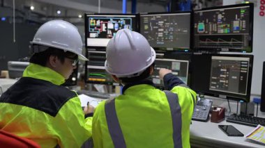 Büyük Endüstri Fabrikası Erkek Bilgisayar Mühendisleri Kişisel Bilgisayarlar üzerinde çalışıyor kontrol makinesi için kodlama programı, Taylandlılar dört monitör ve ciddi bir programcıyla çalışıyorlar.