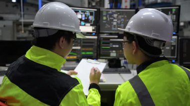 Büyük Endüstri Fabrikası Erkek Bilgisayar Mühendisleri Kişisel Bilgisayarlar üzerinde çalışıyor kontrol makinesi için kodlama programı, Taylandlılar dört monitör ve ciddi bir programcıyla çalışıyorlar.