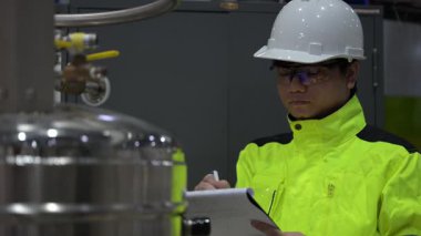 Operasyon salonunda çalışan Asyalı mühendis, Taylandlı adam kask takıyor, özen ve sabırla çalışıyor, hidrojen tankının kapakçık düzenleyicisini kontrol ediyor..