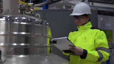 Operasyon salonunda çalışan Asyalı mühendis, Taylandlı adam kask takıyor, özen ve sabırla çalışıyor, hidrojen tankının kapakçık düzenleyicisini kontrol ediyor..