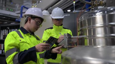 Operasyon salonunda çalışan Asyalı mühendisler, Taylandlılar kask takıyor, gayret ve sabırla çalışıyorlar, hidrojen tankında valf düzenleyicilerini kontrol ediyorlar..