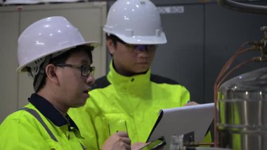 Operasyon salonunda çalışan Asyalı mühendisler, Taylandlılar kask takıyor, gayret ve sabırla çalışıyorlar, hidrojen tankında valf düzenleyicilerini kontrol ediyorlar..