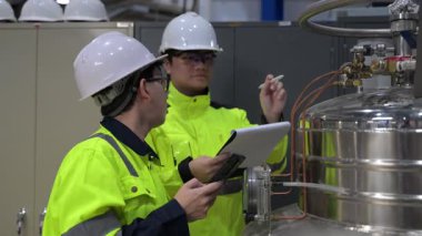 Operasyon salonunda çalışan Asyalı mühendisler, Taylandlılar kask takıyor, gayret ve sabırla çalışıyorlar, hidrojen tankında valf düzenleyicilerini kontrol ediyorlar..