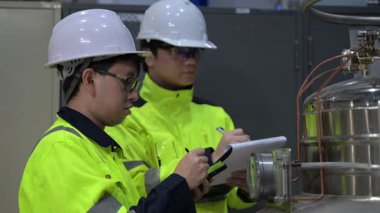 Operasyon salonunda çalışan Asyalı mühendisler, Taylandlılar kask takıyor, gayret ve sabırla çalışıyorlar, hidrojen tankında valf düzenleyicilerini kontrol ediyorlar..