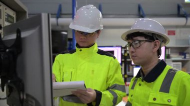 Büyük Endüstri Fabrikası Erkek Bilgisayar Mühendisleri Kişisel Bilgisayarlar üzerinde çalışıyor kontrol makinesi için kodlama programı, Taylandlılar dört monitör ve ciddi bir programcıyla çalışıyorlar.