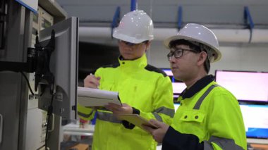 Büyük Endüstri Fabrikası Erkek Bilgisayar Mühendisleri Kişisel Bilgisayarlar üzerinde çalışıyor kontrol makinesi için kodlama programı, Taylandlılar dört monitör ve ciddi bir programcıyla çalışıyorlar.