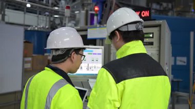 Büyük Endüstri Fabrikası Erkek Bilgisayar Mühendisleri Kişisel Bilgisayarlar üzerinde çalışıyor kontrol makinesi için kodlama programı, Taylandlılar dört monitör ve ciddi bir programcıyla çalışıyorlar.