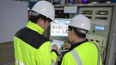 Büyük Endüstri Fabrikası Erkek Bilgisayar Mühendisleri Kişisel Bilgisayarlar üzerinde çalışıyor kontrol makinesi için kodlama programı, Taylandlılar dört monitör ve ciddi bir programcıyla çalışıyorlar.