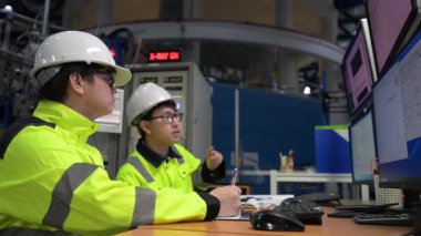 Büyük Endüstri Fabrikası Erkek Bilgisayar Mühendisleri Kişisel Bilgisayarlar üzerinde çalışıyor kontrol makinesi için kodlama programı, Taylandlılar dört monitör ve ciddi bir programcıyla çalışıyorlar.