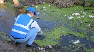 Kirli bir nehirde su kalitesini ölçen adam. 