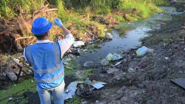 Kirli bir nehirde su kalitesini ölçen adam. 