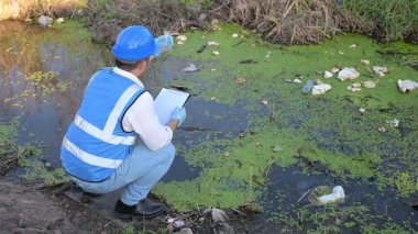 Adam çöplerle dolu nehirde su kalitesini kontrol ediyor. Kirlilik sorunu kavramı 